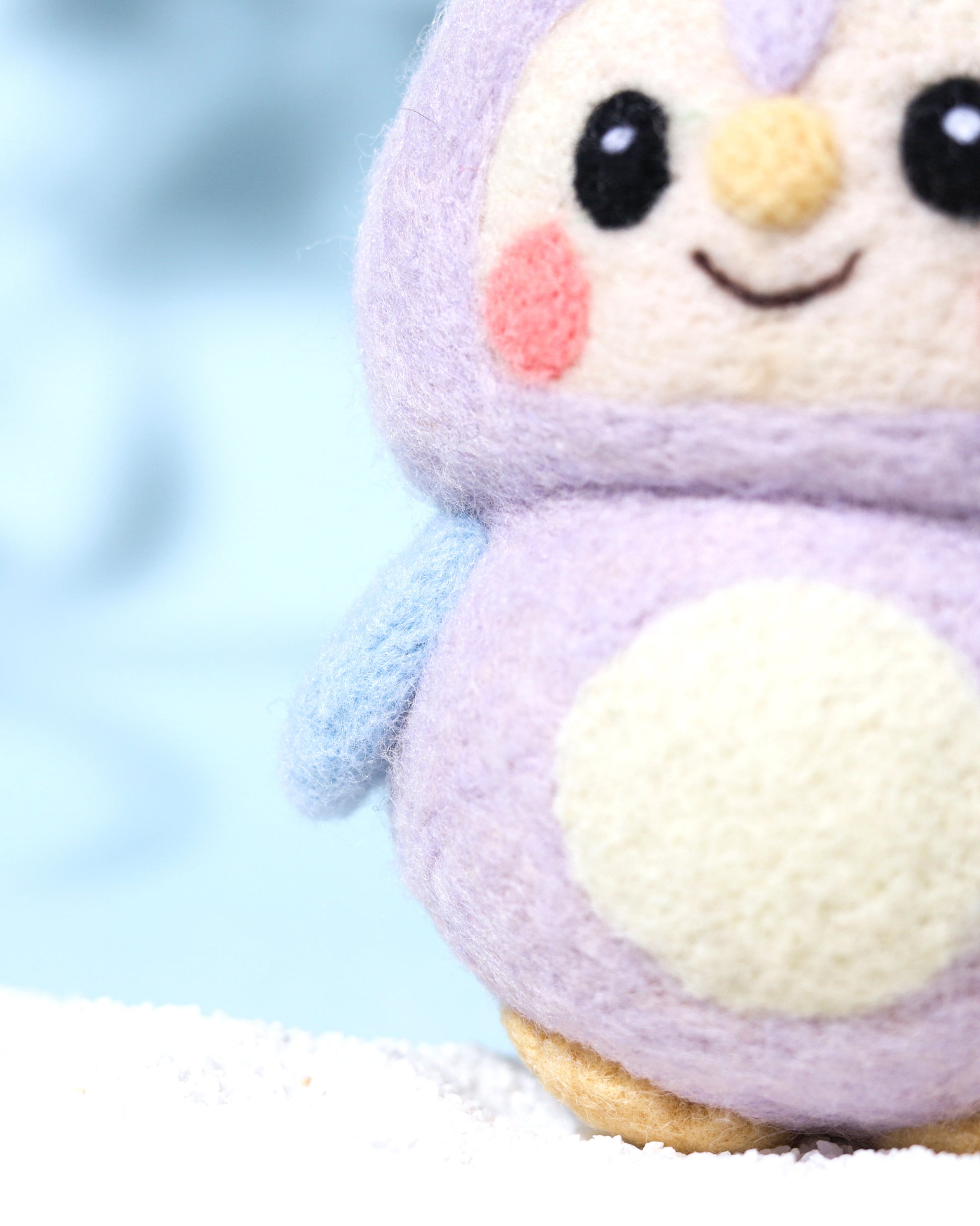 Close-up detail of purple needle-felted owl charm showing the fuzzy natural wool texture, pink blushed cheeks, and heart-shaped face design.