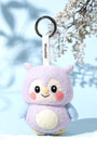 Cute purple owl wool keychain standing on white sand with artistic leaf shadows, designed in Austin as a sustainable slow-fashion accessory